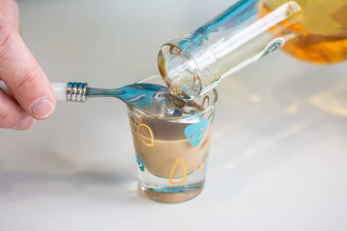 Layering a shot by pouring Irish Whiskey over the back of a spoon into a shot glass 3/4 full with irish cream