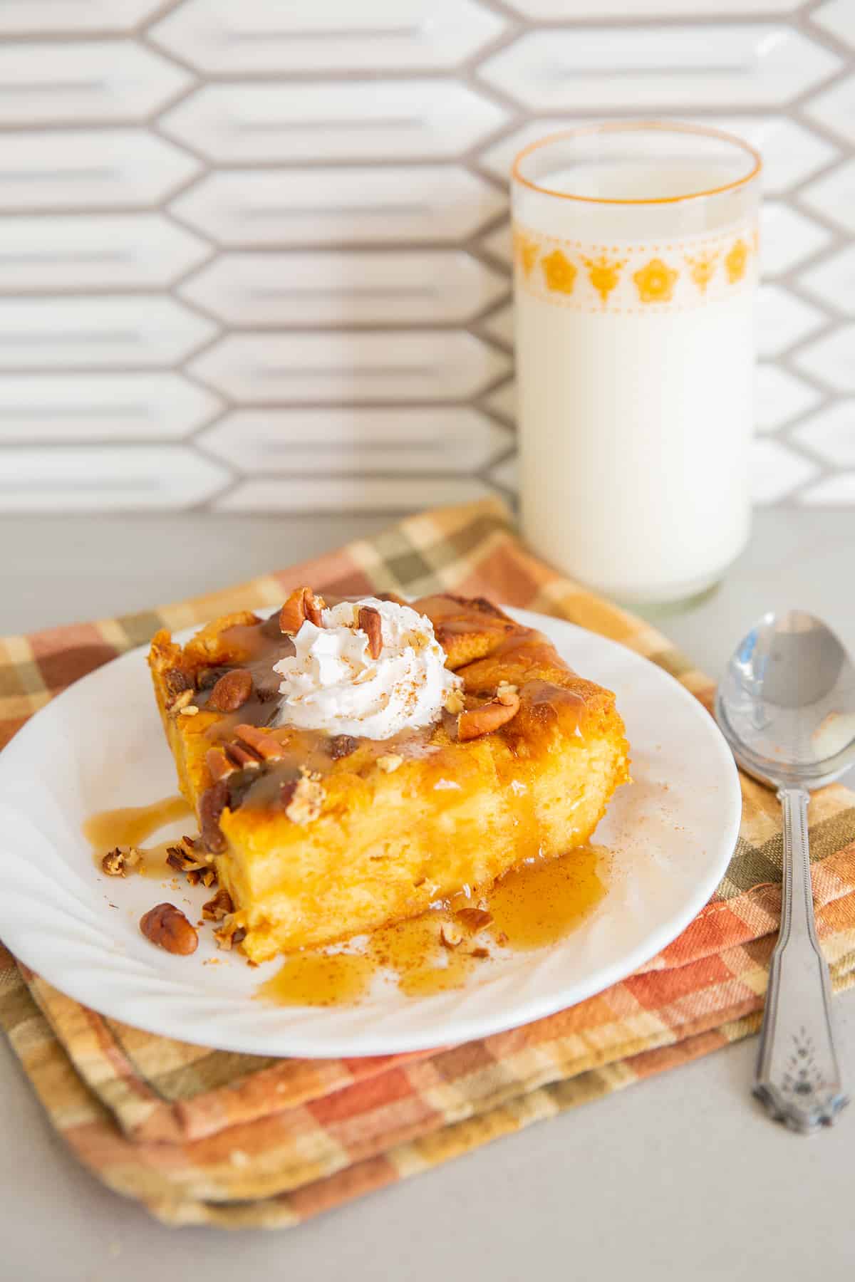 Pumpkin Bread Pudding on a white plate, a glass of milk on background