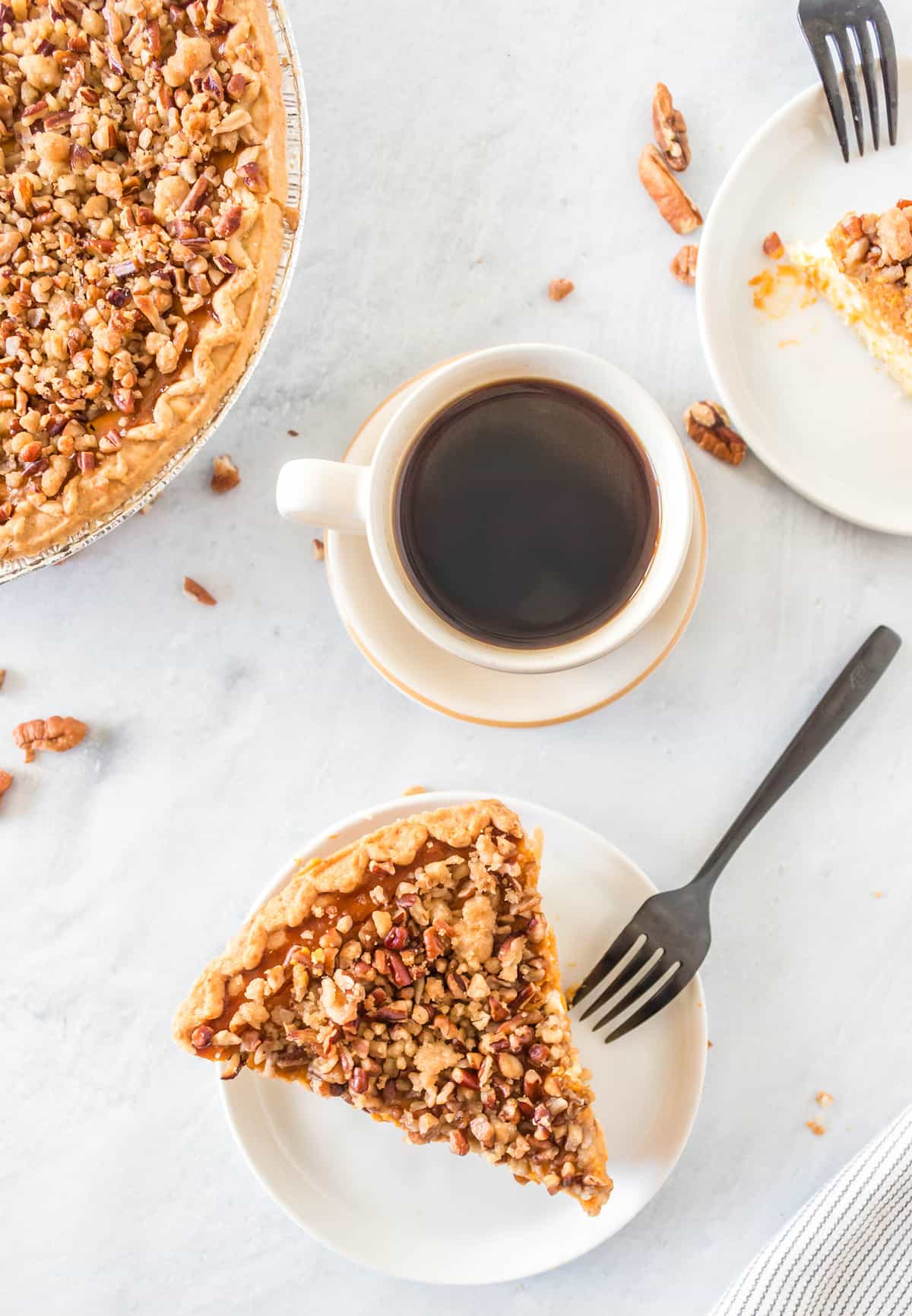 top down shot of Pumpkin Cheesecake Pie slice in a white plate and a cup of coffee beside it