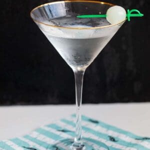 Gibson Cocktail on a black background garnished with pickled onion
