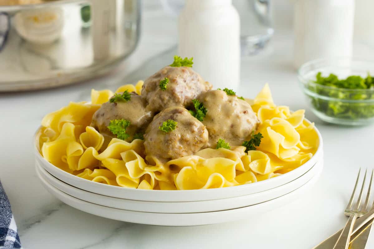creamy swedish meatballs on a bed of noodles on a white plate