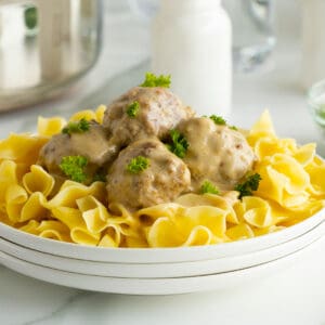 creamy swedish meatballs on a bed of noodles on a white plate