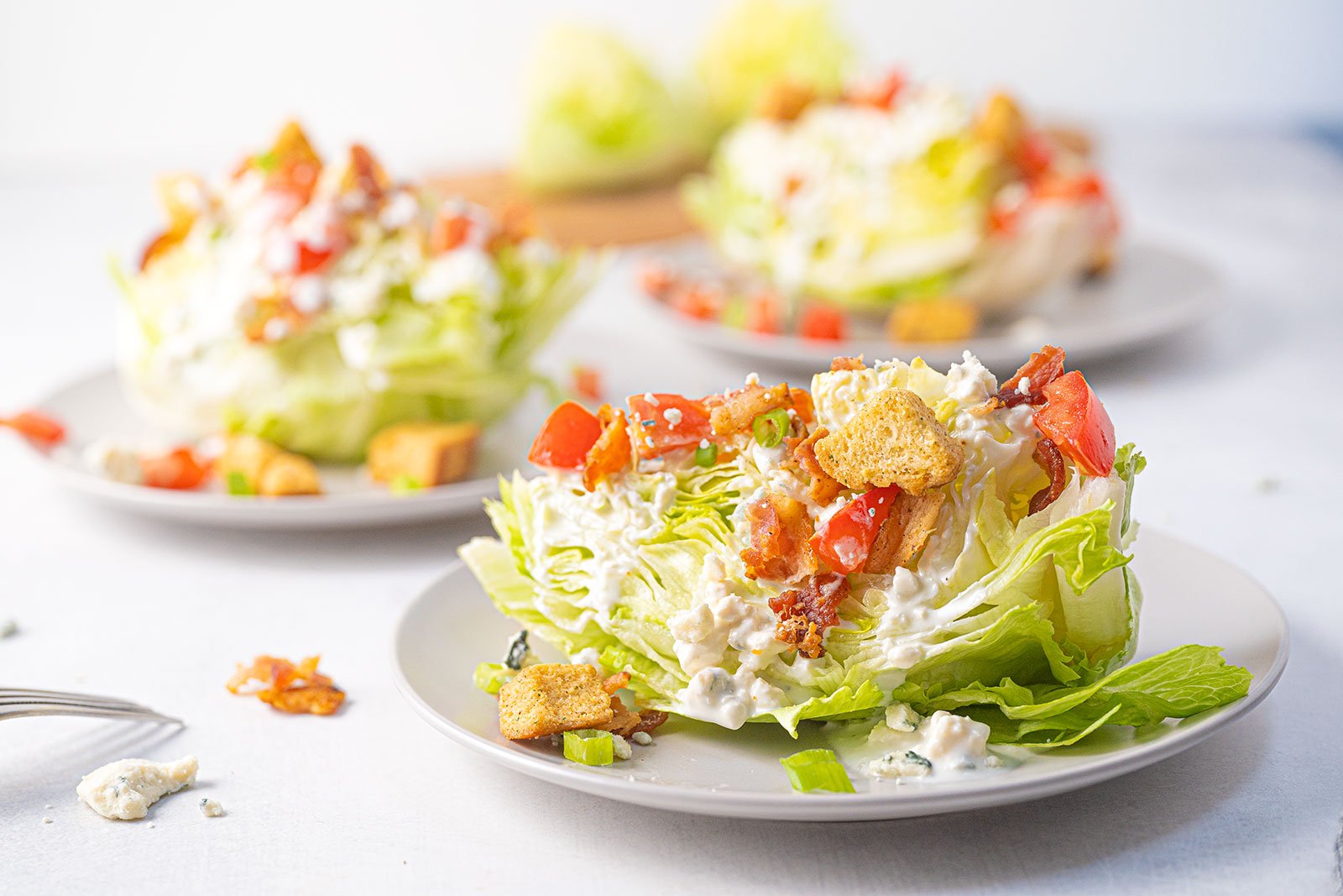 Crisp iceberg lettuce wedge topped with blue cheese dressing, bacon, and tomatoes.