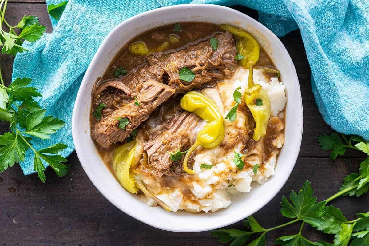 Top down photo of a finished Mississippi pot roast, topped with pepperoncini peppers