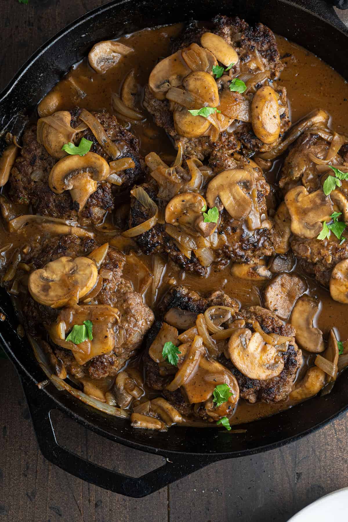 Finish Salisbury steak in a cast iron pan, topped with mushrooms and flecked parsley