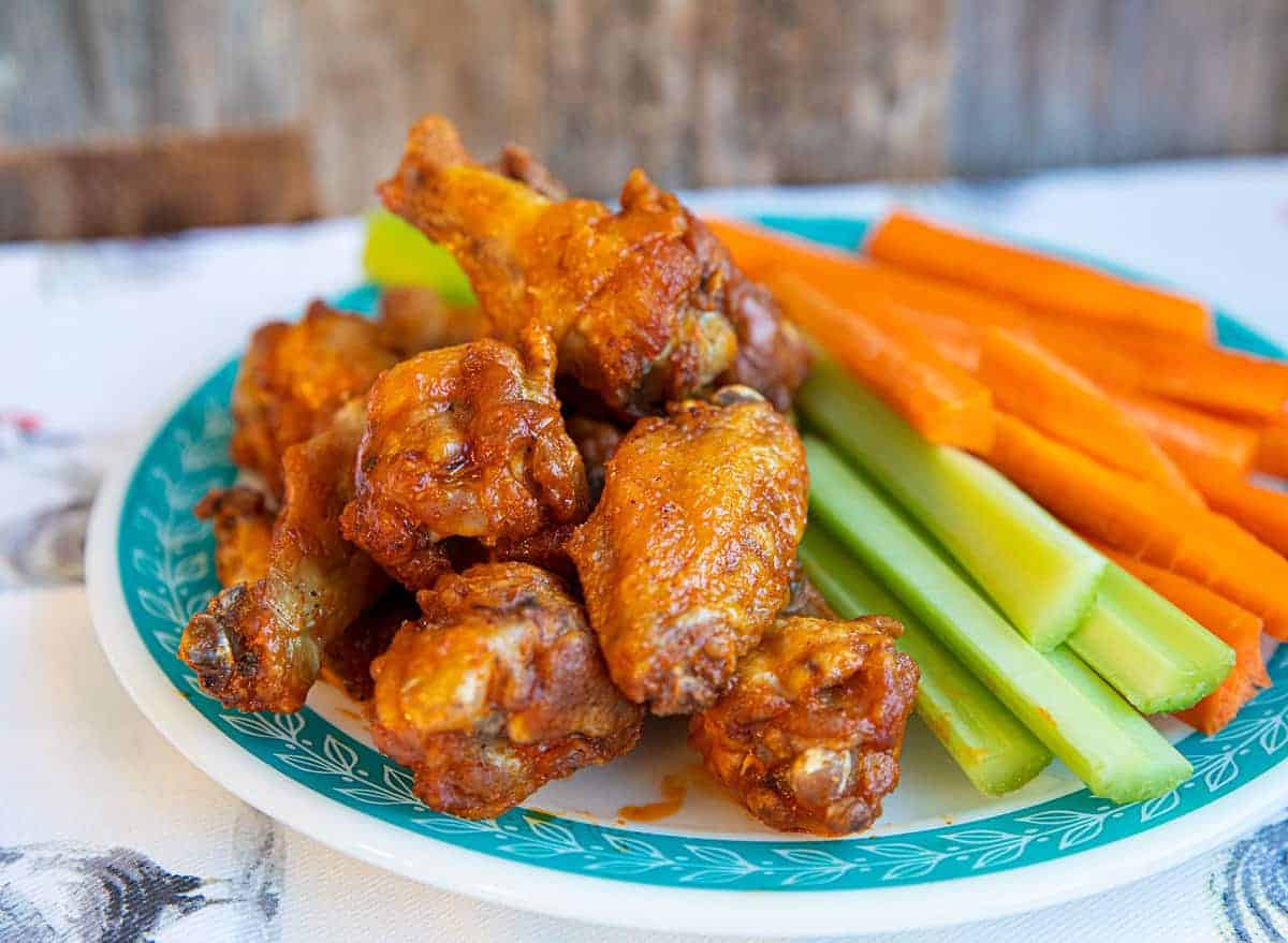 Buffalo Wings stacked on a plate with carrot sticks and celery sticks