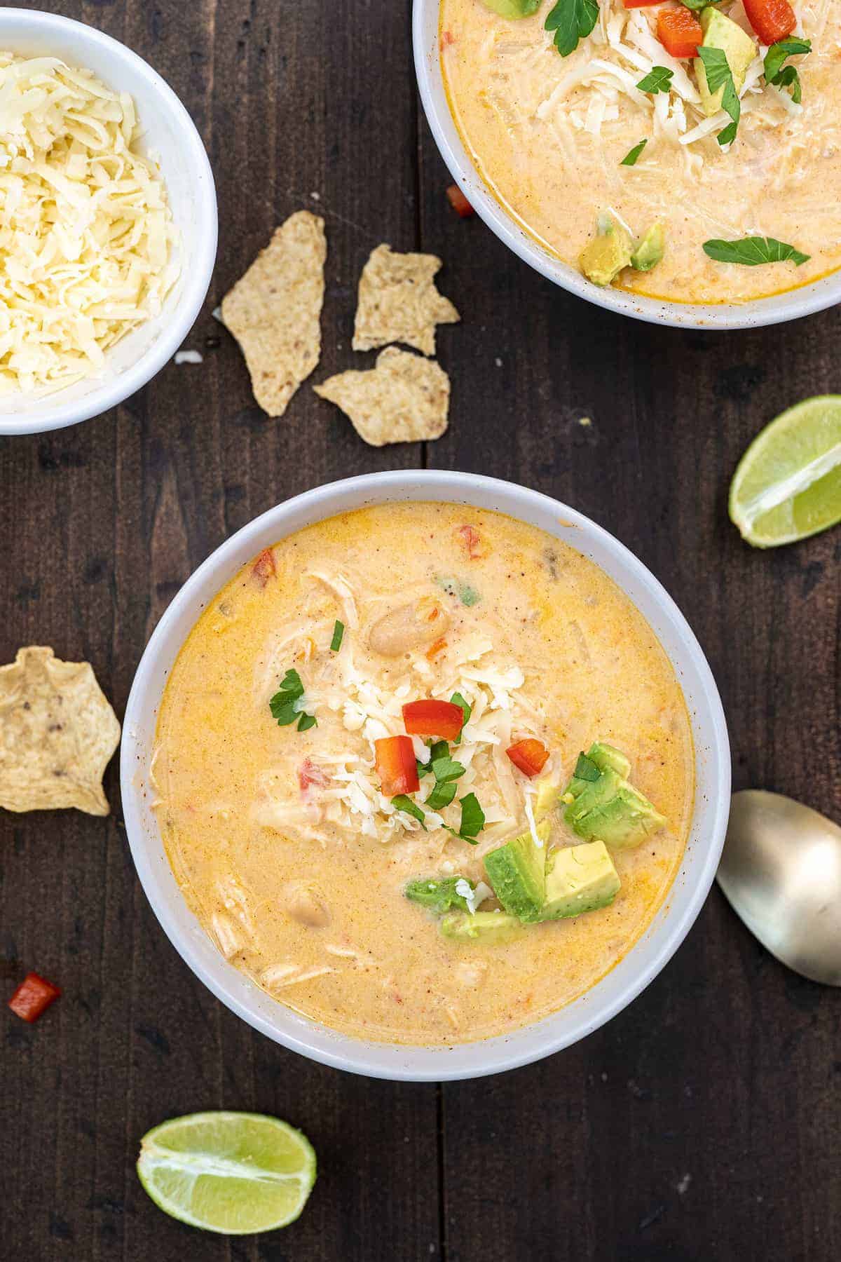 Top down photo of two bowls of Instant Pot white chicken chili, next to lime wedges and corn chips.