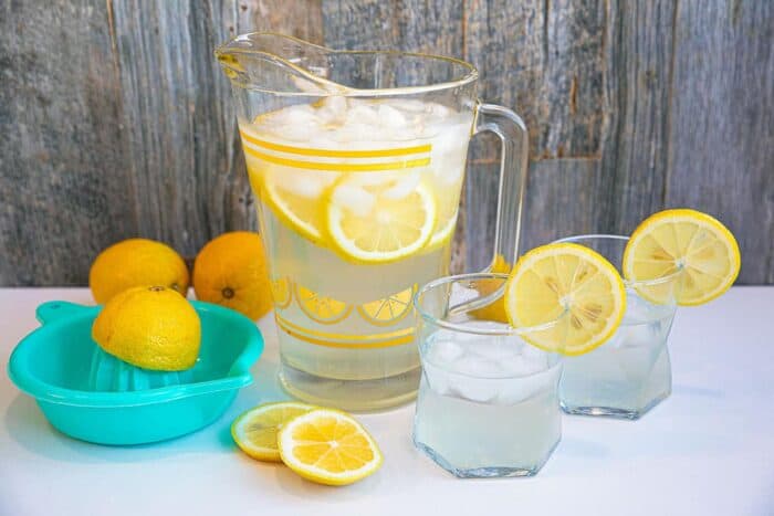 Lemon Water on the counter in two glasses with a pitcher in the background