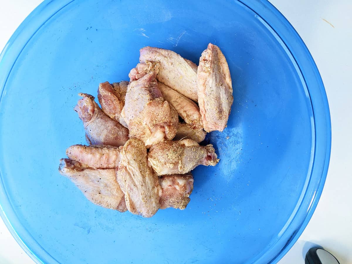 Chicken wings in a bowl covered in spice.