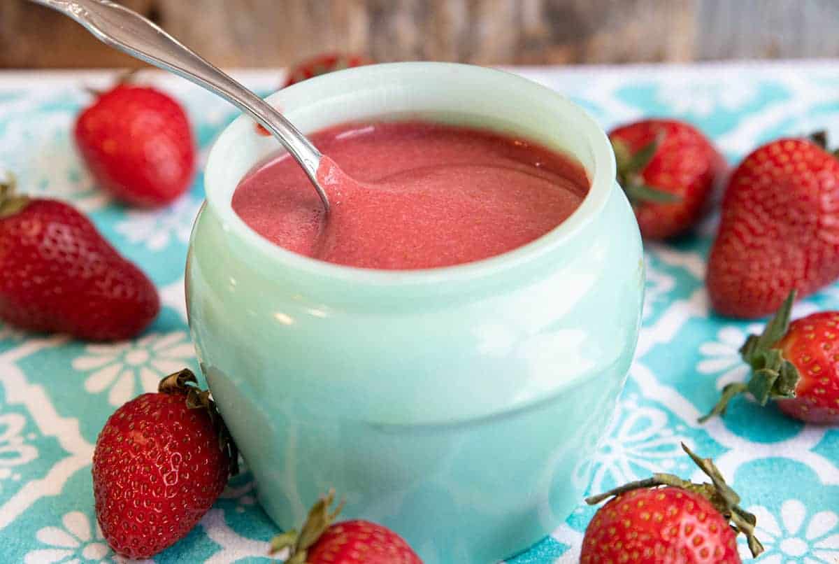 strawberry puree in a green glass jar with a spoon in it