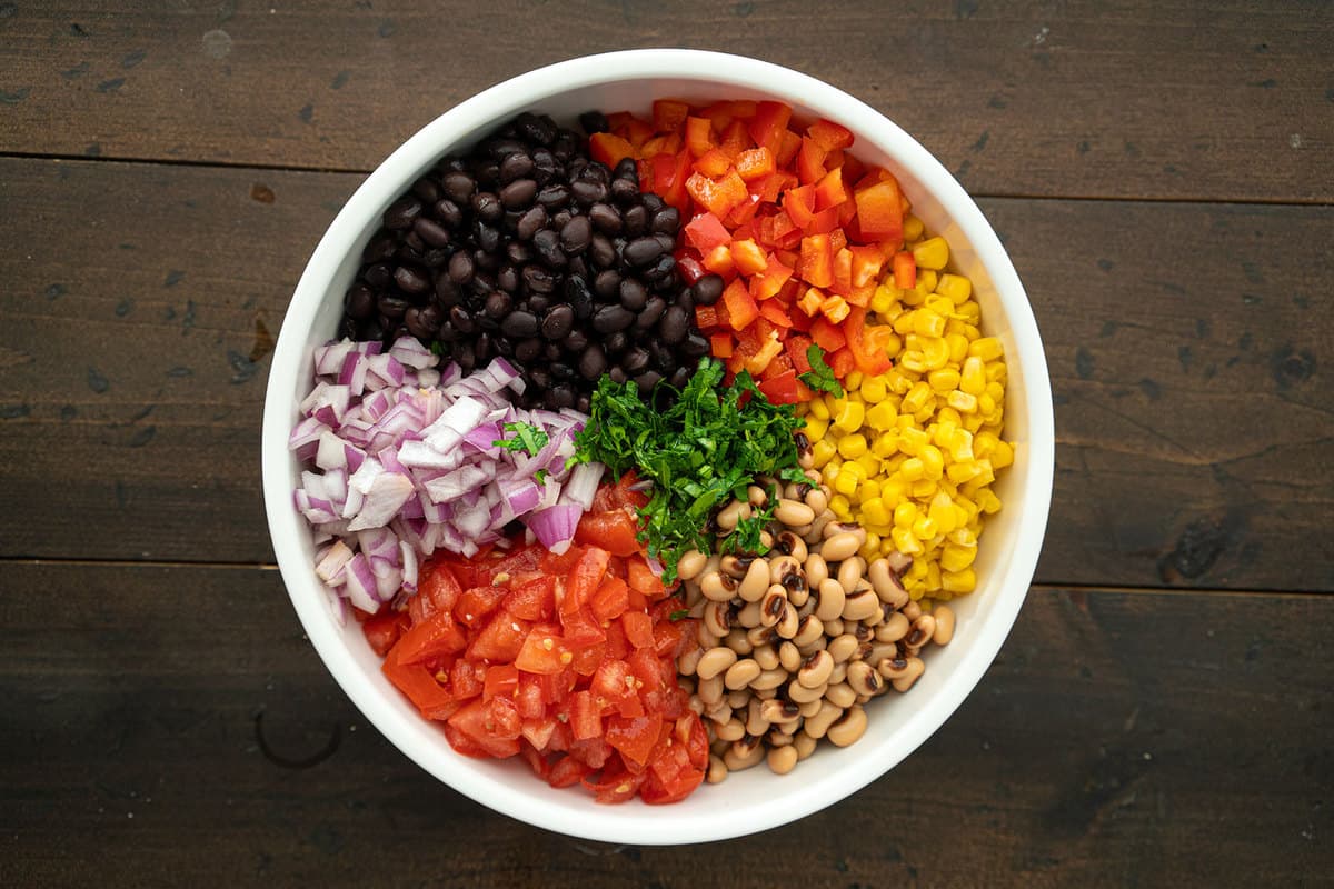 The main ingredients for Cowboy caviar, arranged in color order, in a large mixing bowl.