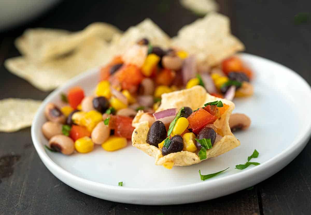 Tortilla chip cups filled with cowboy caviar on a plate.