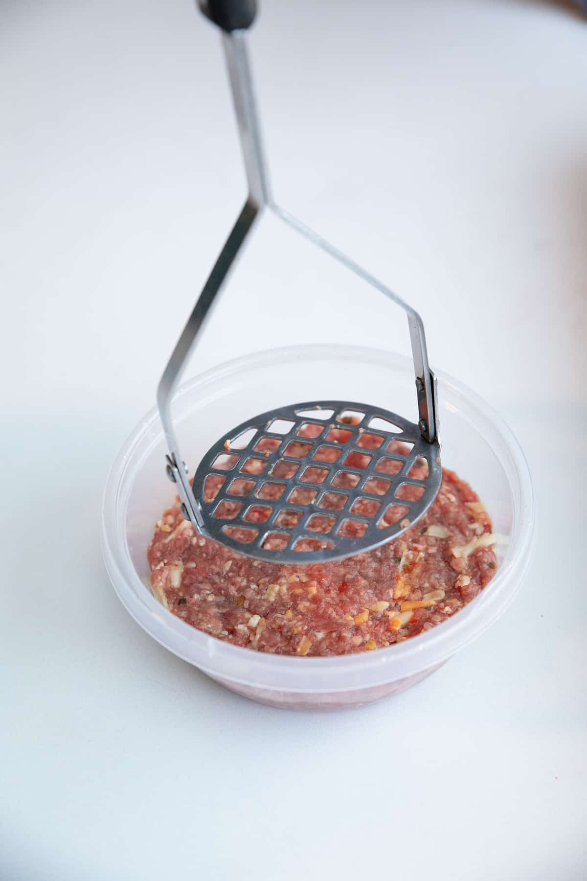 Pressing down the burger mixture into a container to form a patty.