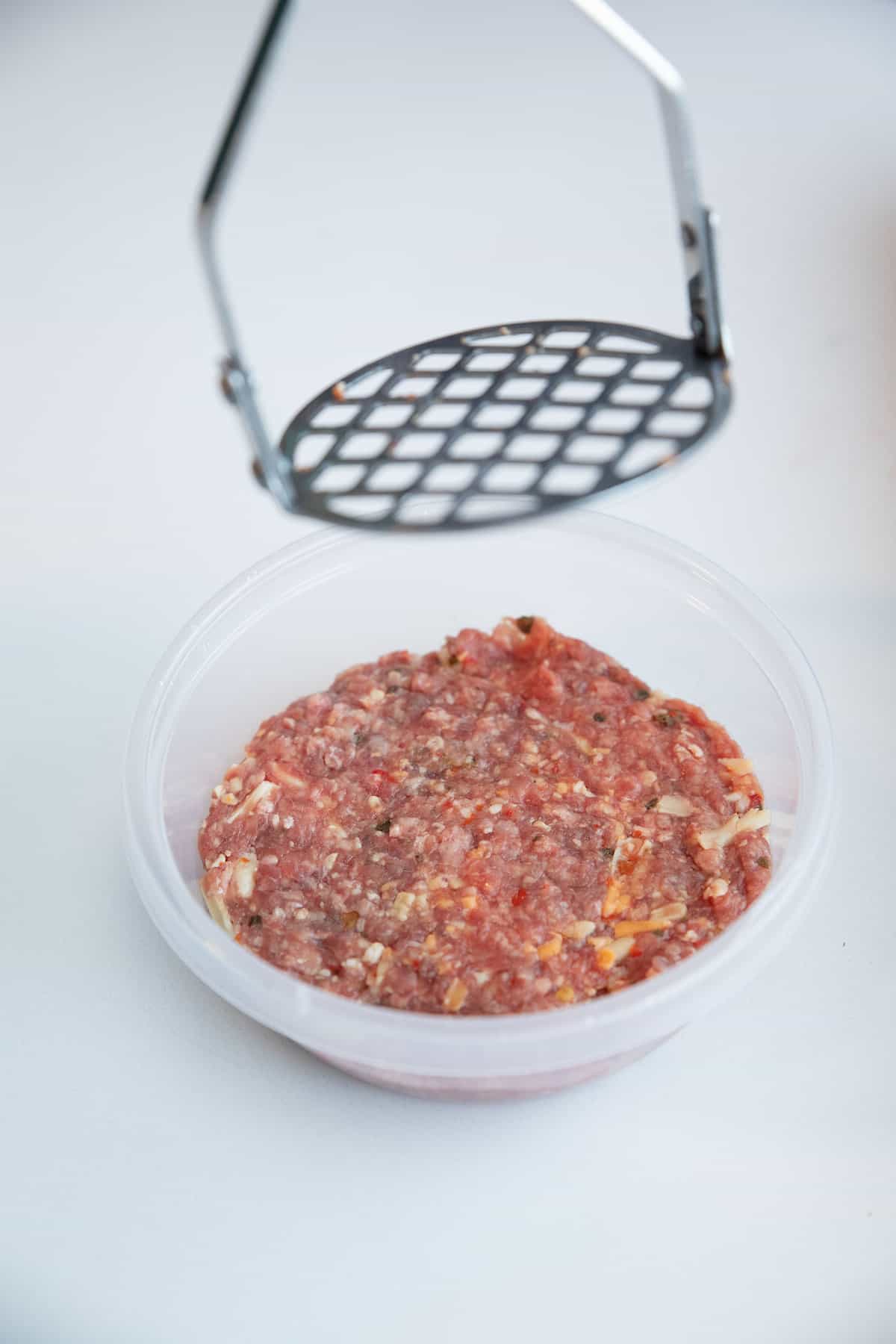 Pressing down the burger mixture into a container to form a patty