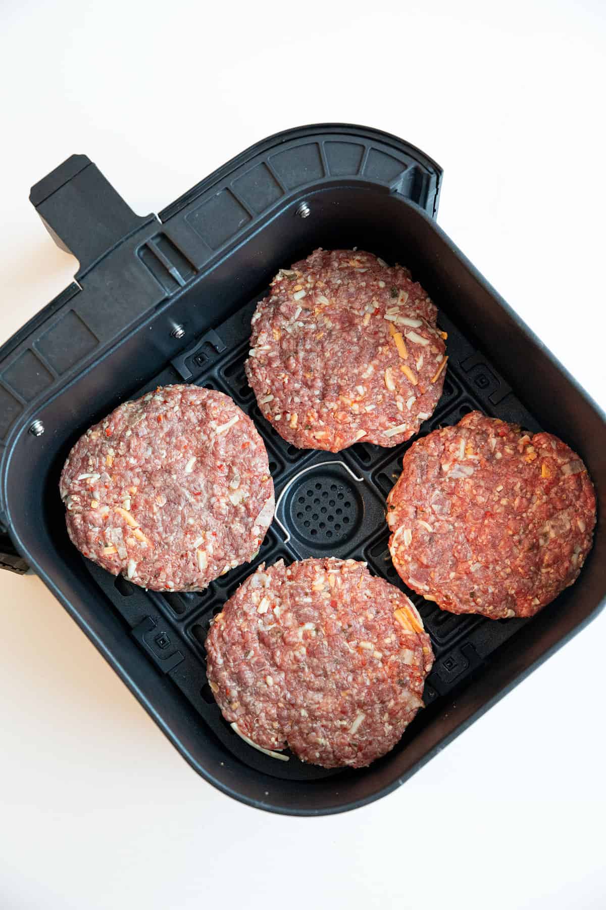 Burger patties in an air fryer basket