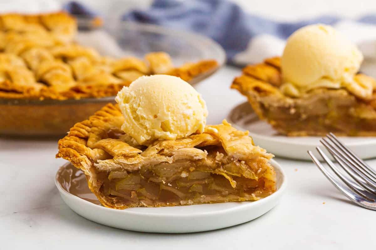 slice of pear pie on a white plate with vanilla ice cream on top