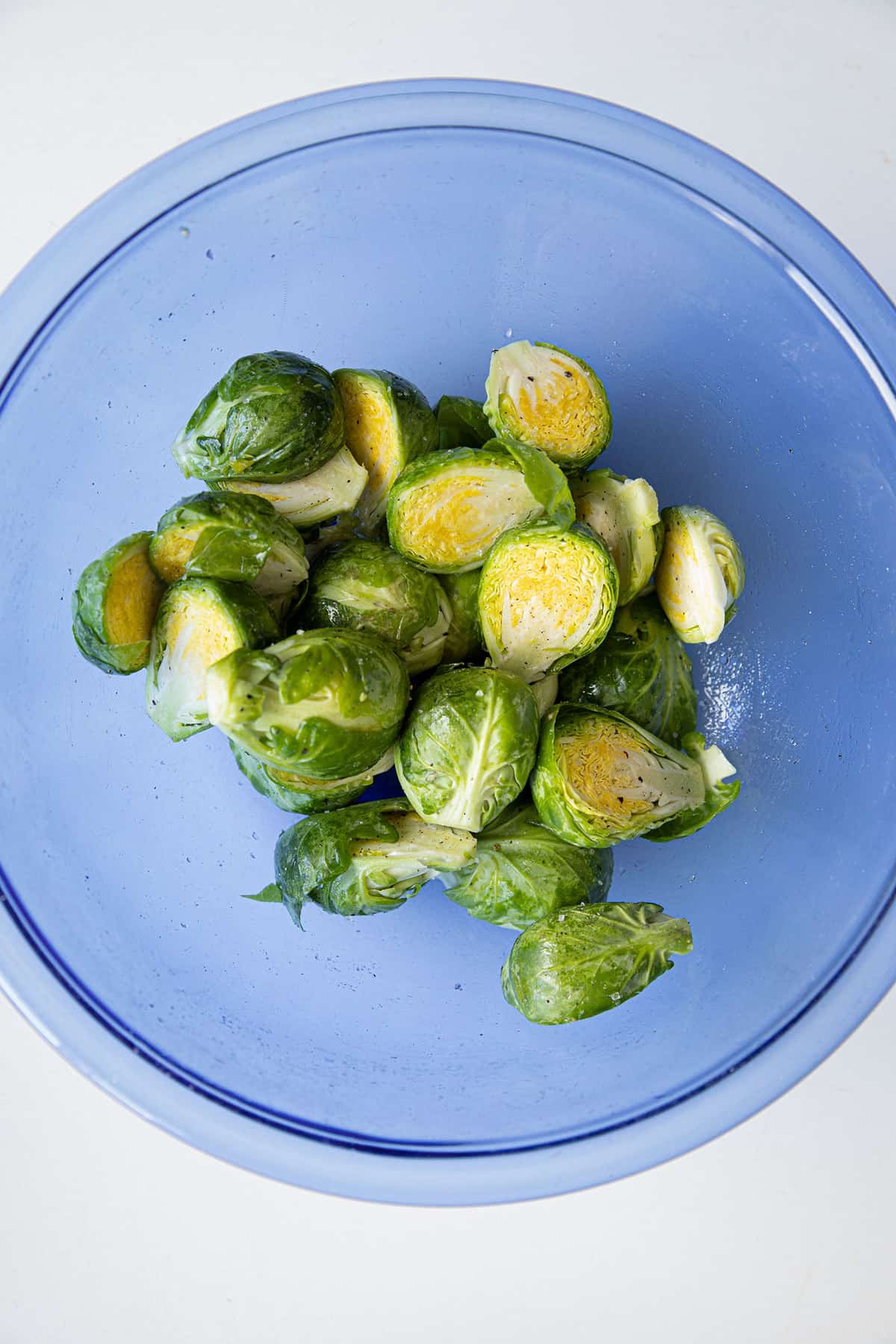 brussel sprouts in a bowl coated in olive oil and salt and pepper