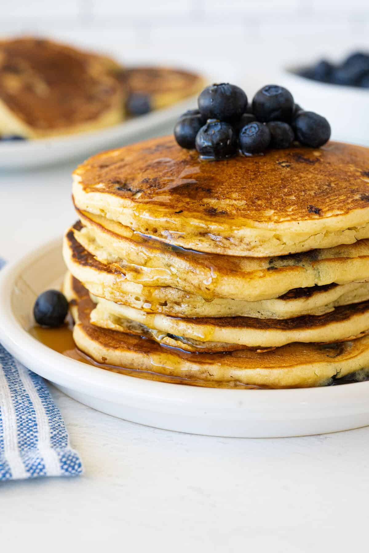 blueberry pancakes on a white plate with syrup pour3ed on them