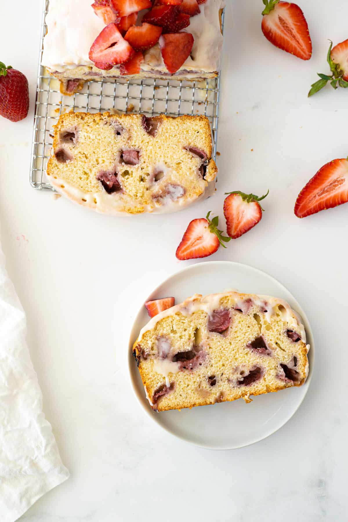 Slice of iced strawberry bread on cooling rack