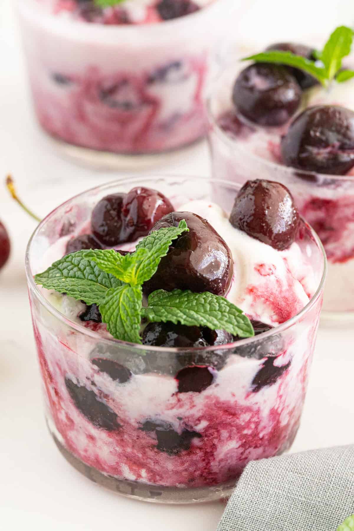 cherries jubilee served over ice cream in a compote and garnished with mint 