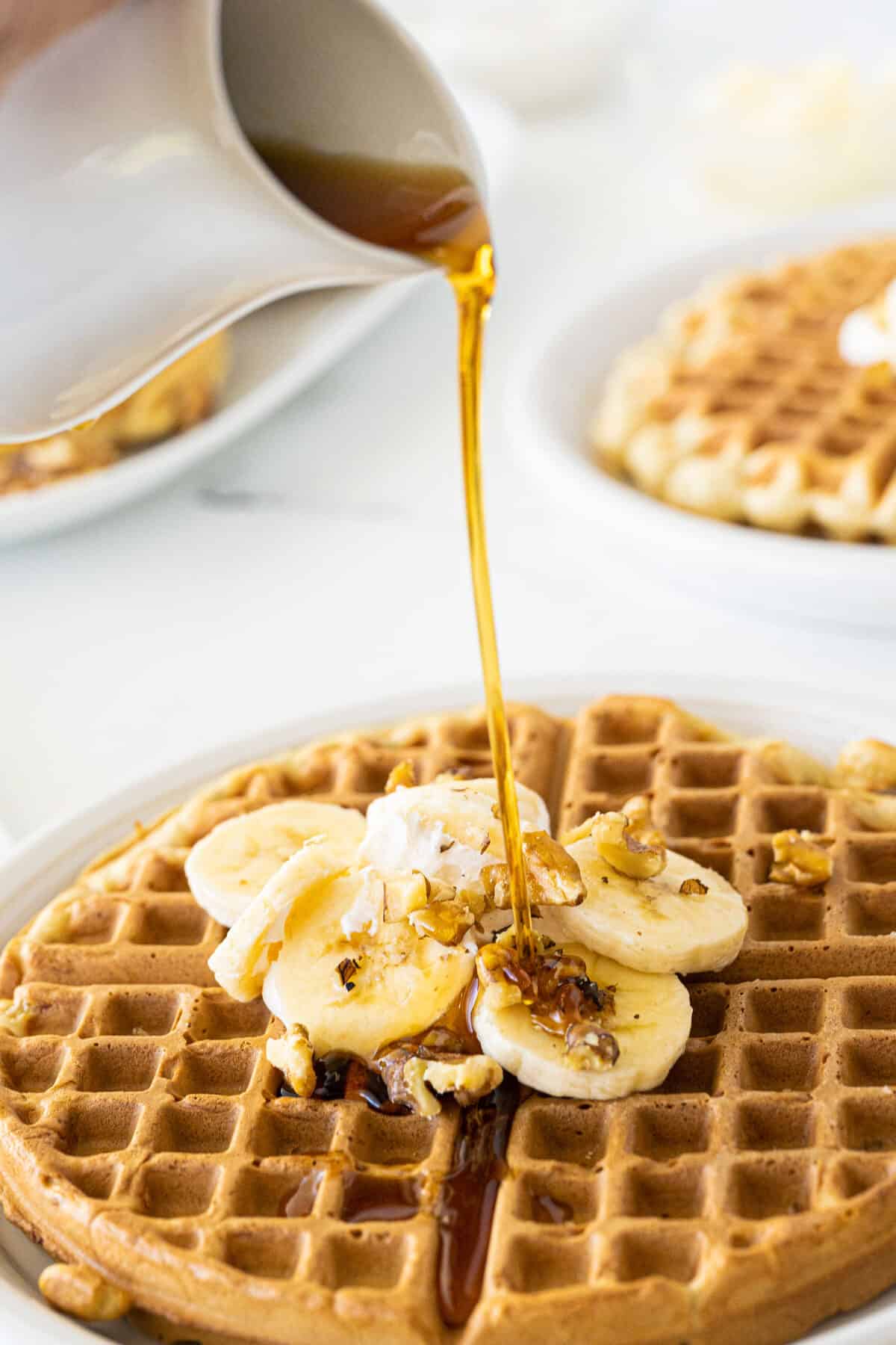 banana waffles with syrup being poured on top