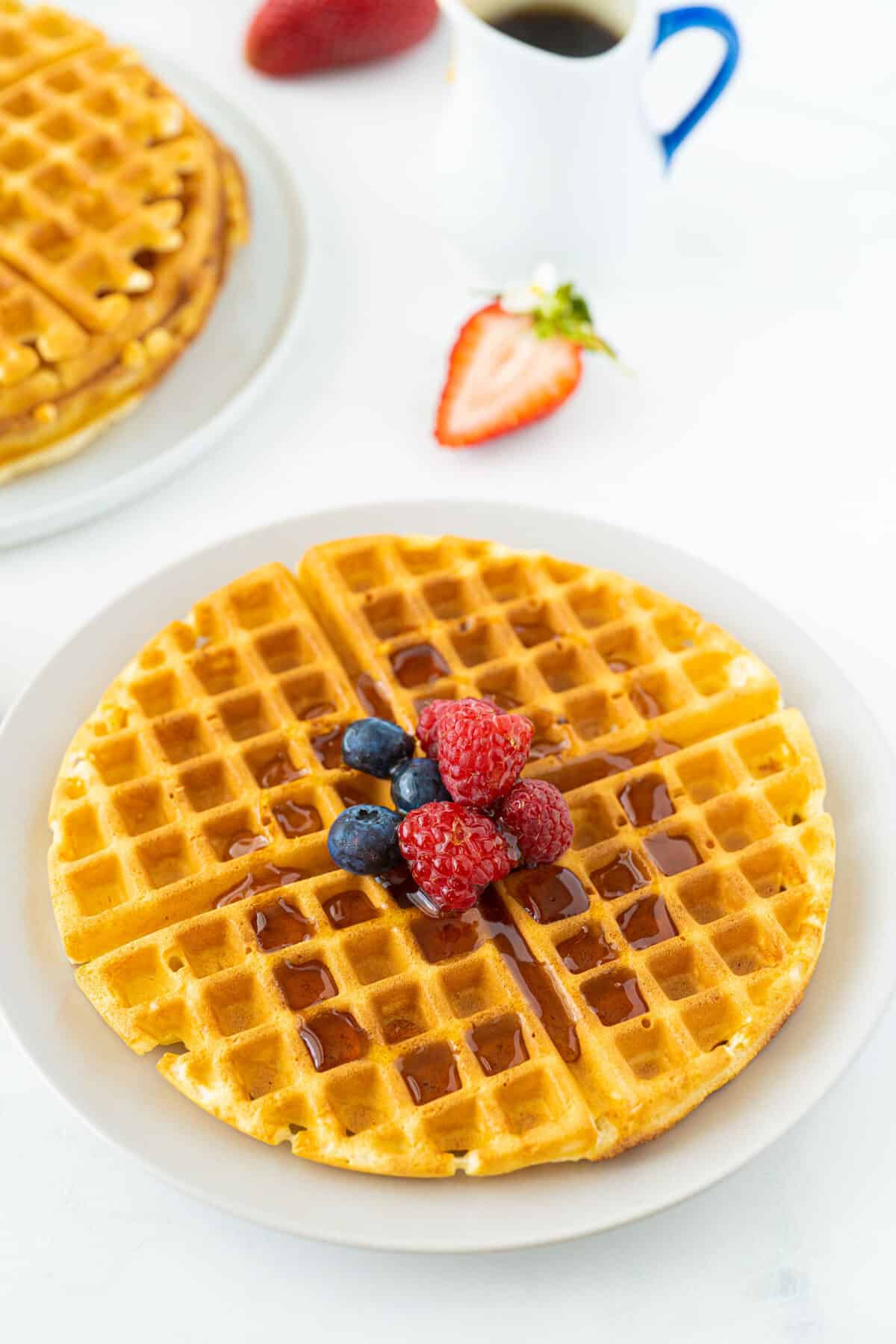 bisquick waffles on a white plate with syrup and berries