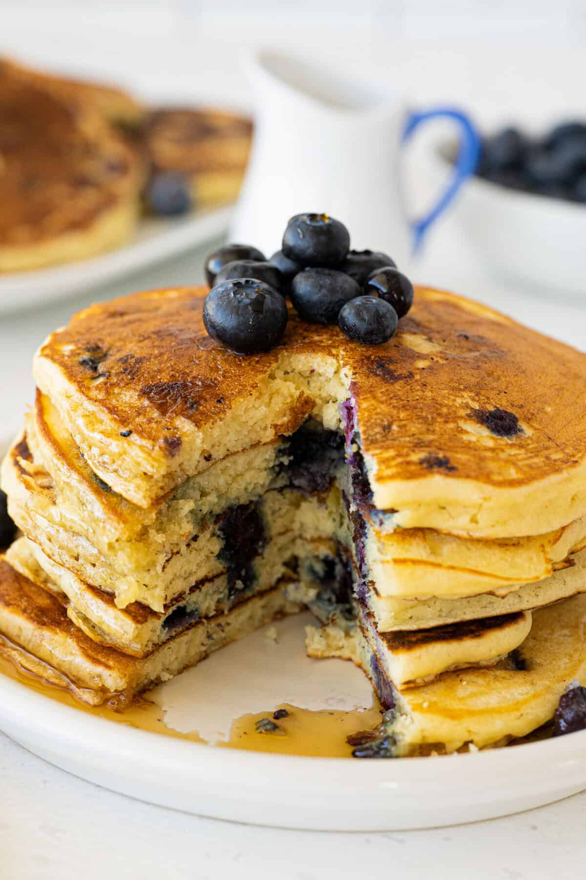 a stack of blueberry pancakes on a white plate