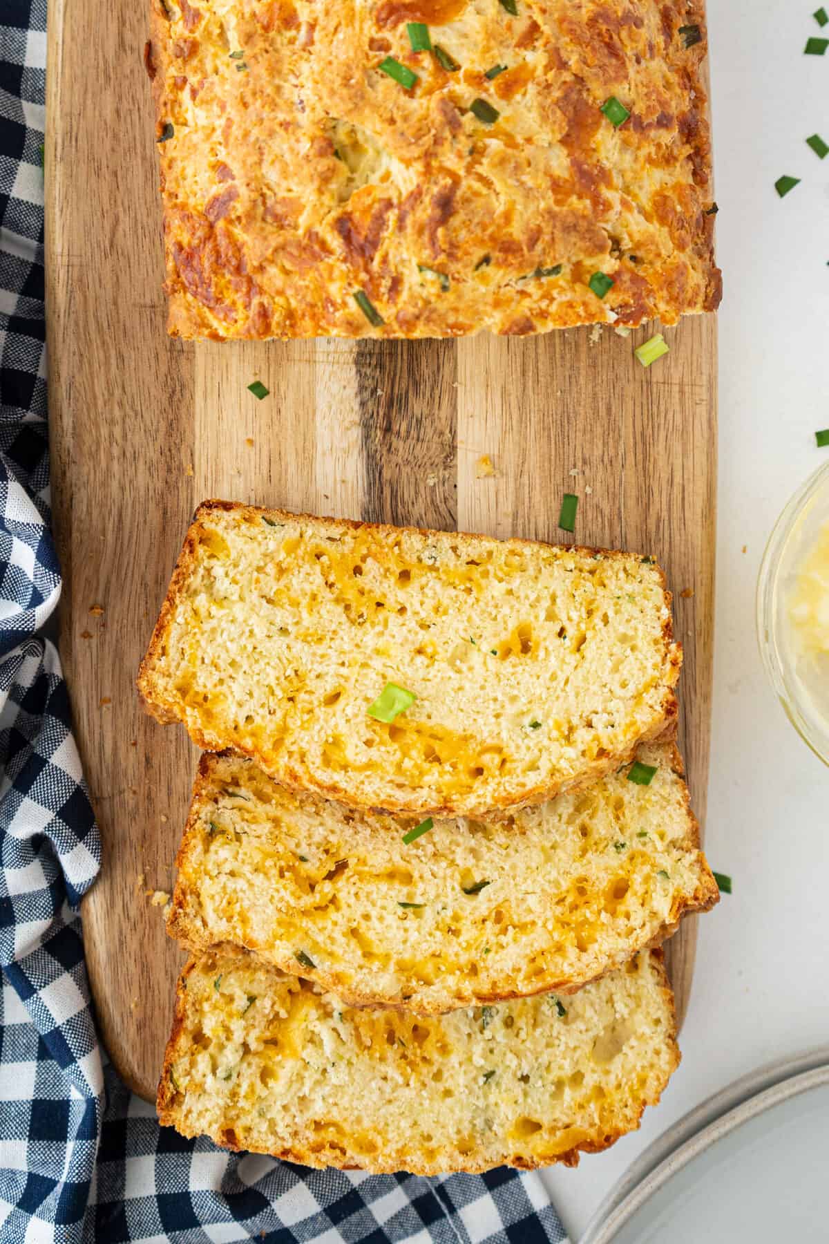 top down shot of cheese bread loaf sliced into pieces on a wooden board 