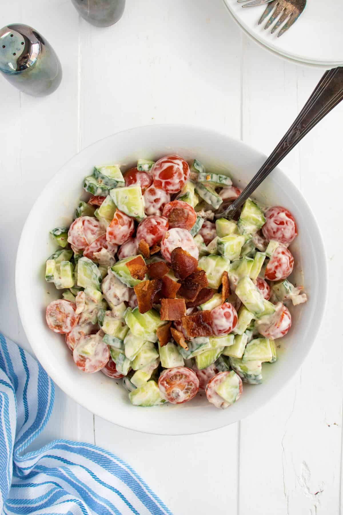 Mixing cucumber tomato salad with a spoon