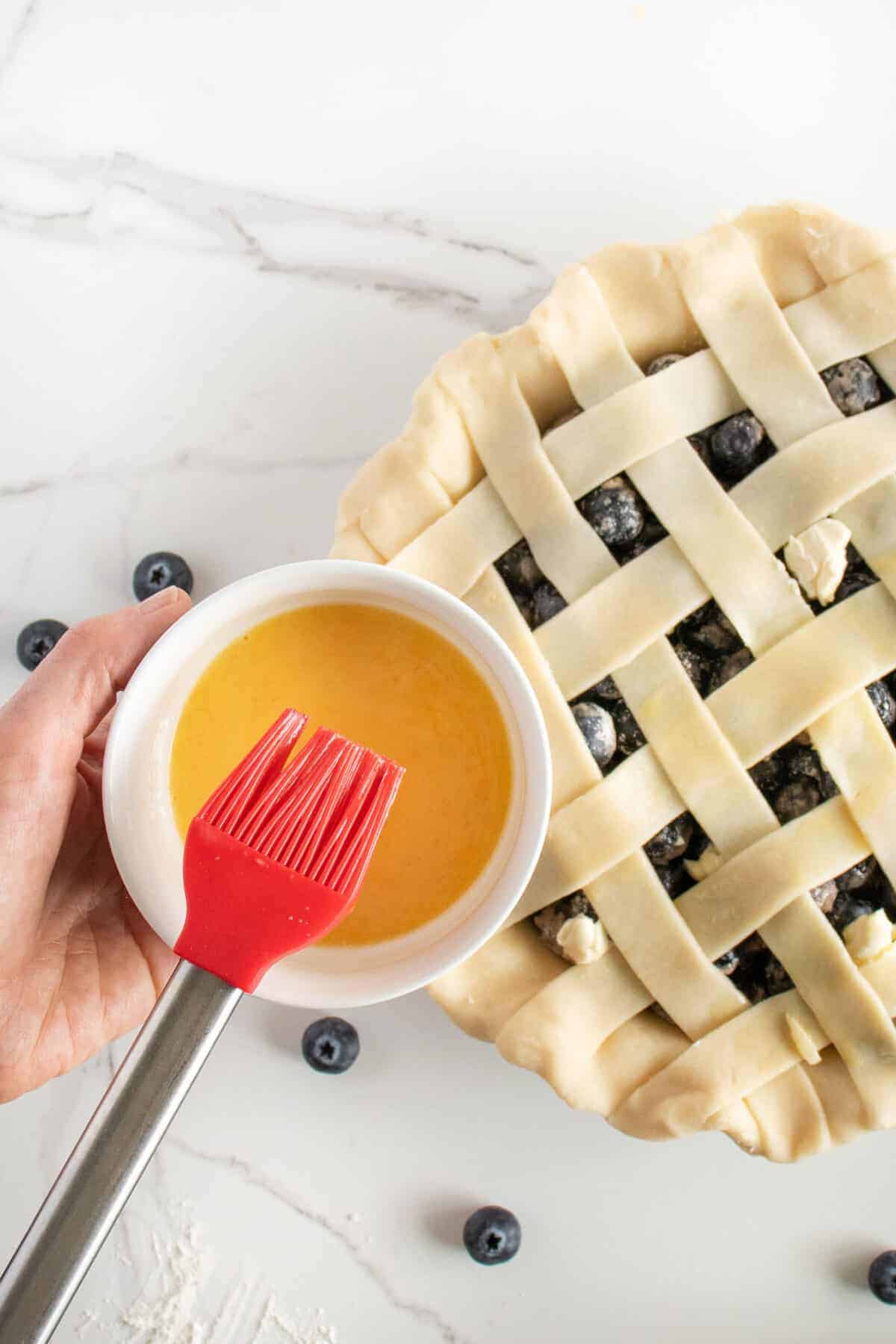 Vertical Shot of an Egg Wash in a Plate with Black Pastry Brush