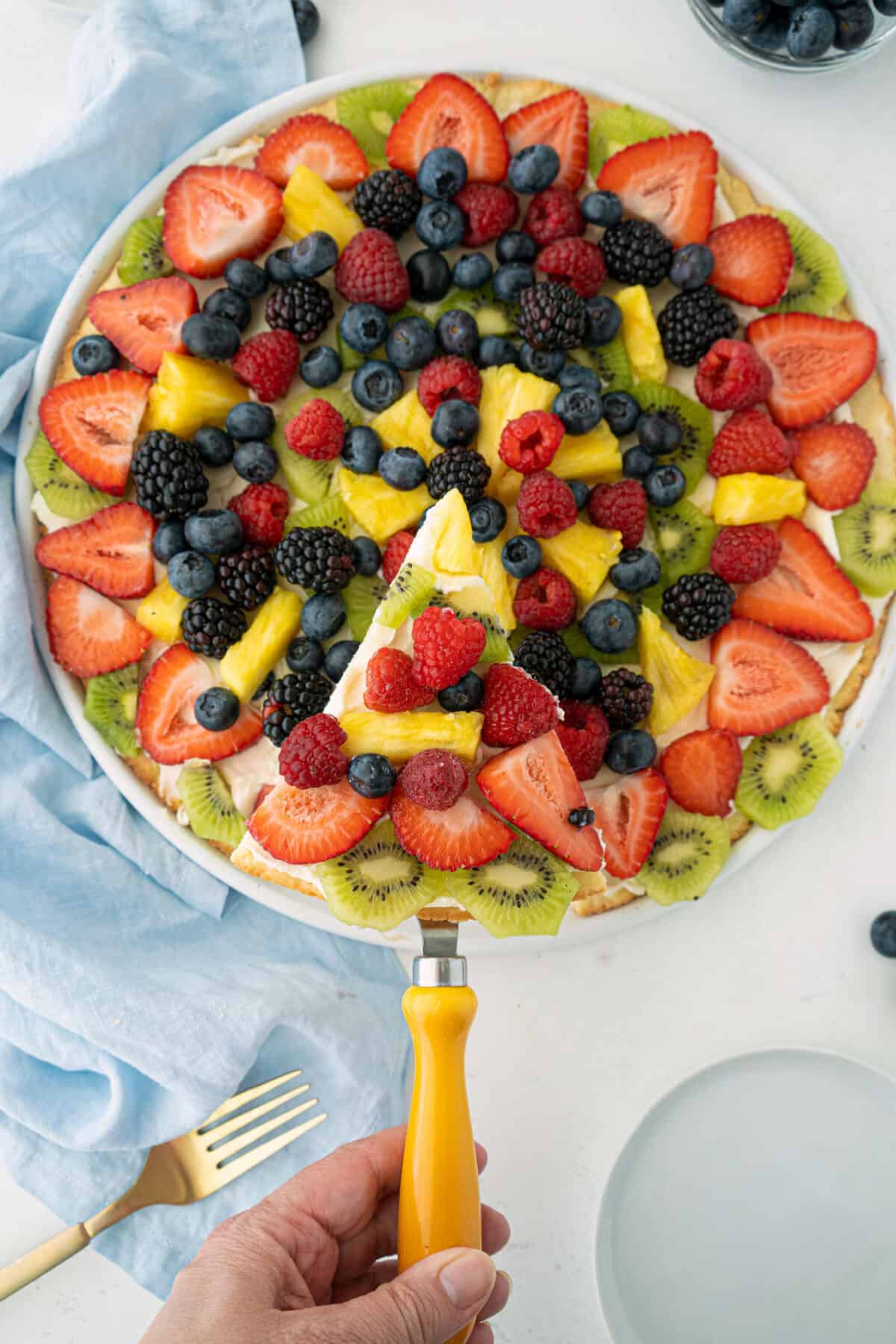 lifting a slice of fruit pizza with a cake lifter