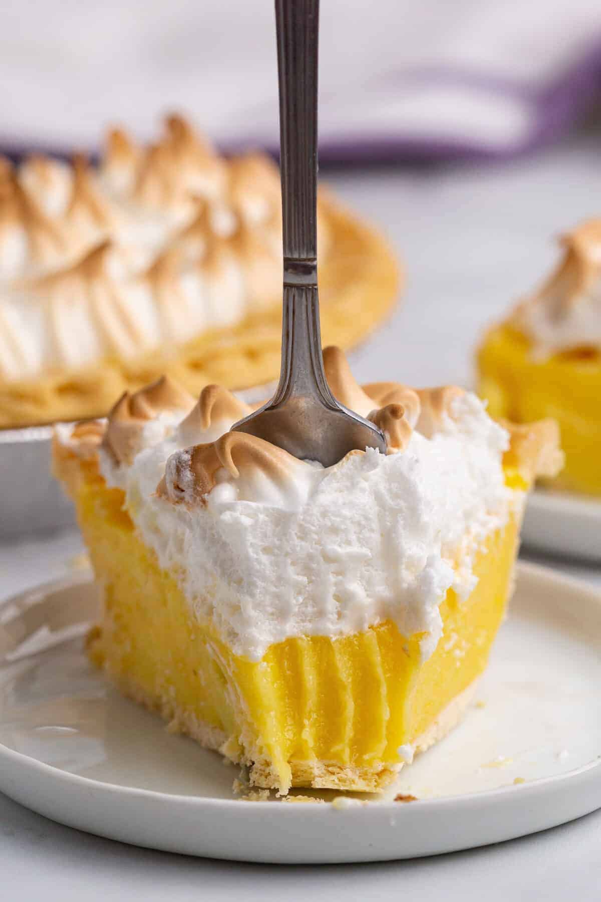 slice of lemon meringue pie with a fork in it 