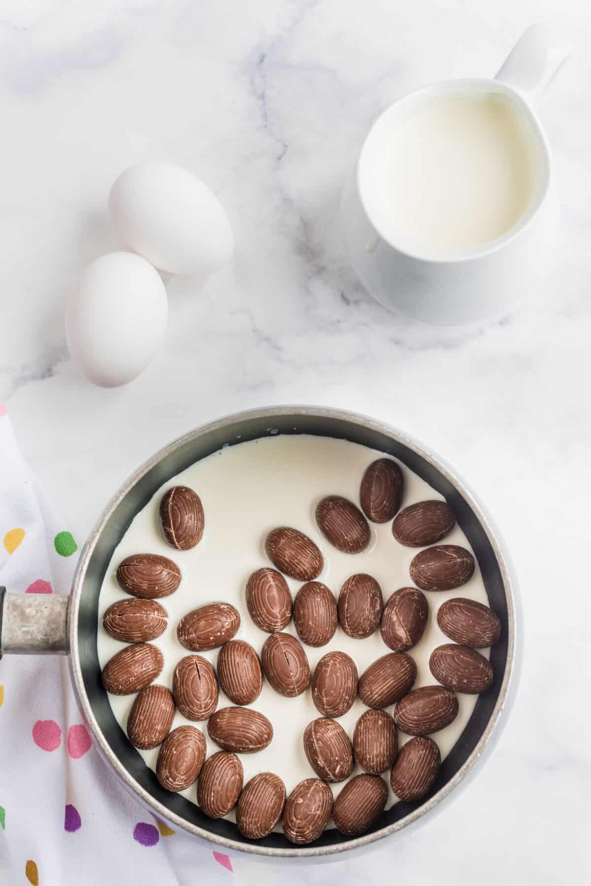 melting chocolate Easter eggs into whipping cream in a pot 