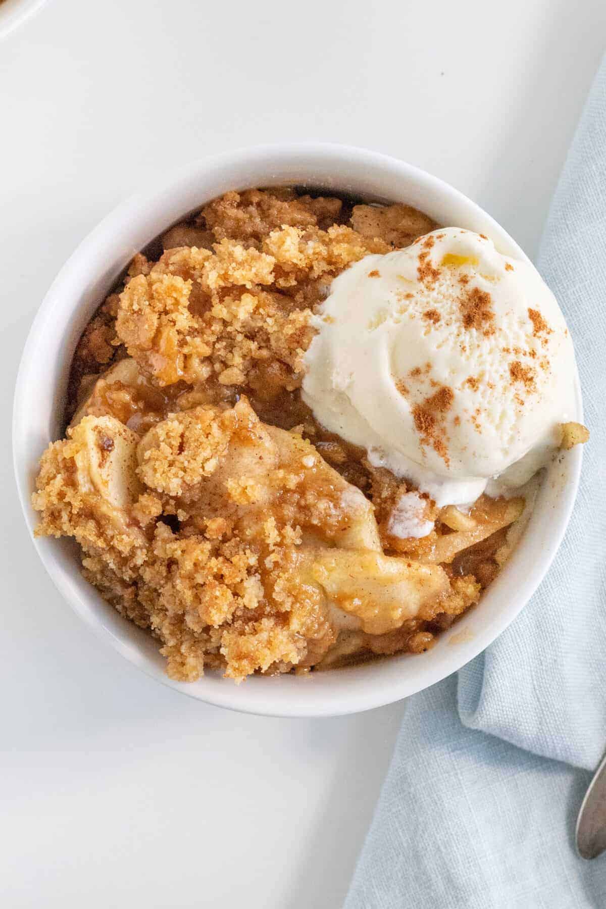 top down shot of apple brown betty in a bowl with vanilla ice cream