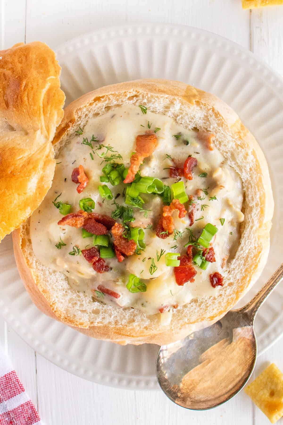 top down shot of clam chowder in a bread bowl with garnishes on top