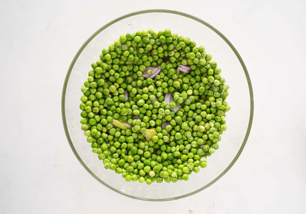 peas on top of onions in a bowl