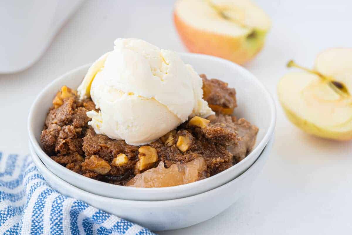 apple dump cake in a bowl with ice cream on top