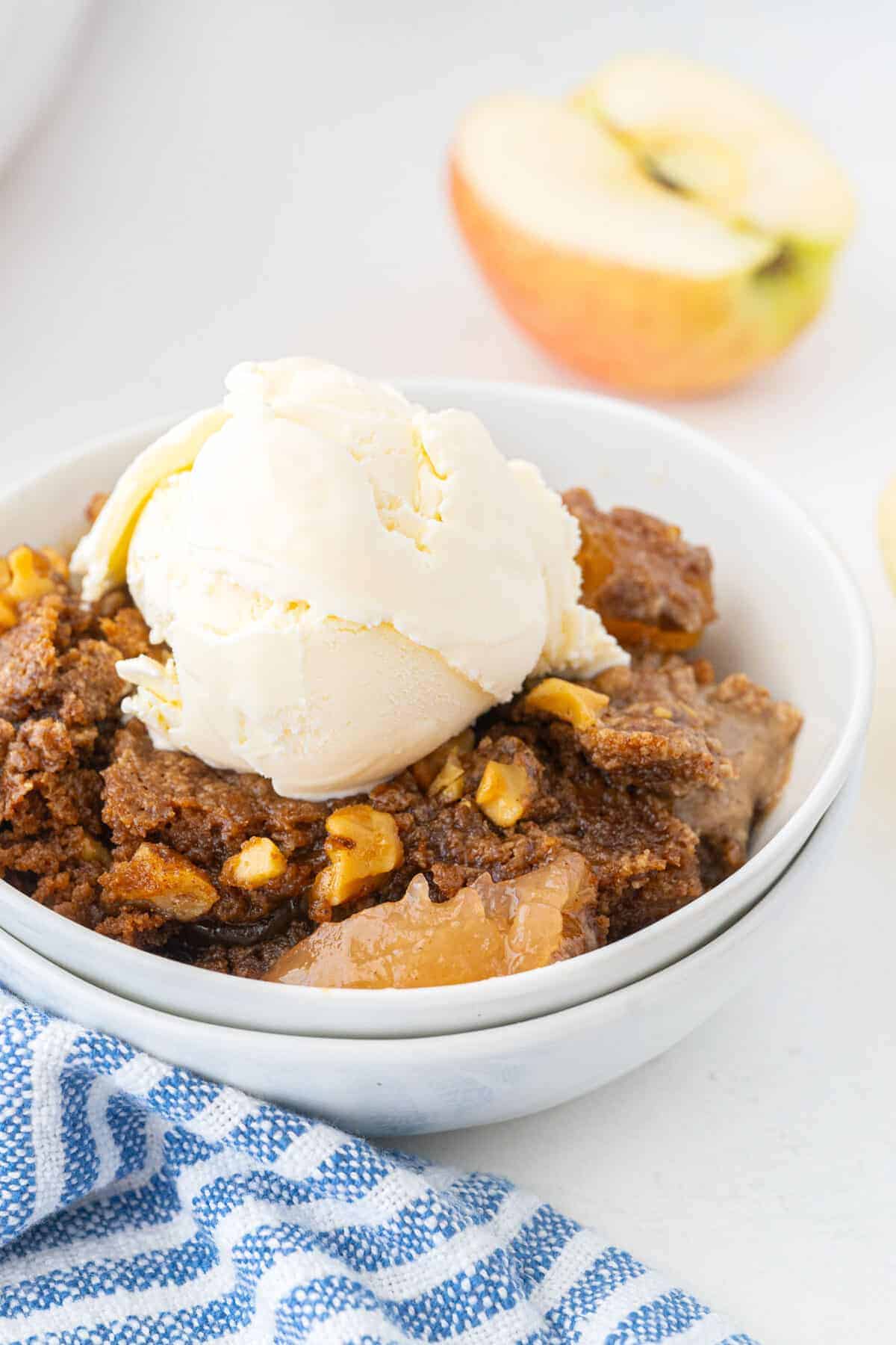 apple dump cake in a bowl with ice cream on top