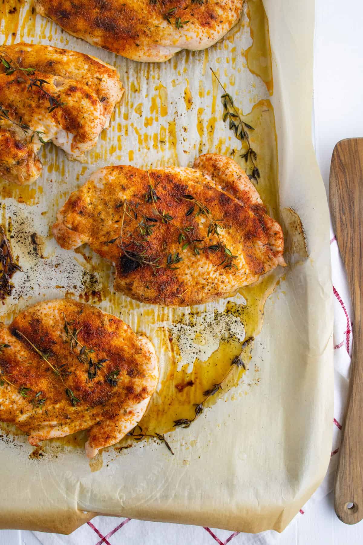 baked chicken breasts on a parchment lined baking sheet