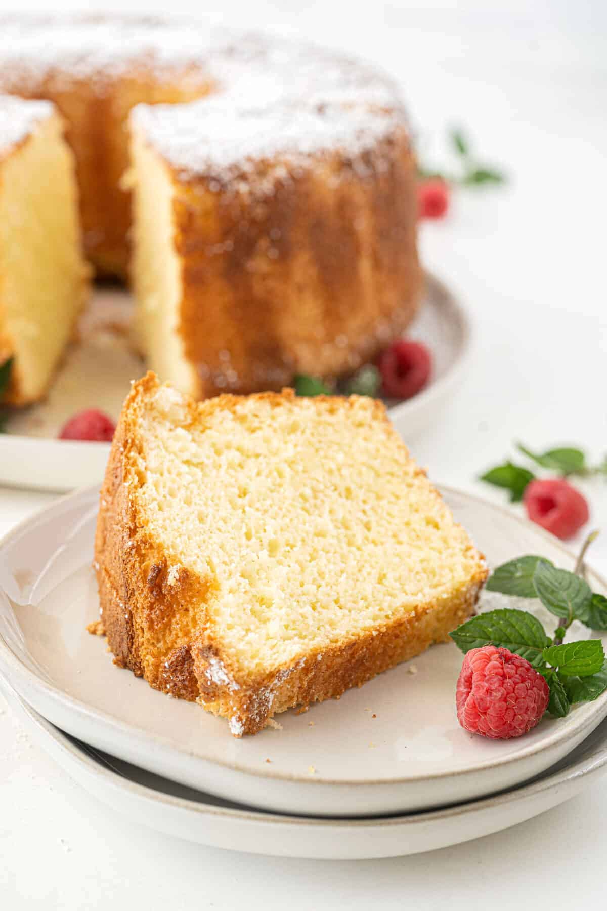 chiffon cake slice on a white plate with raspberries