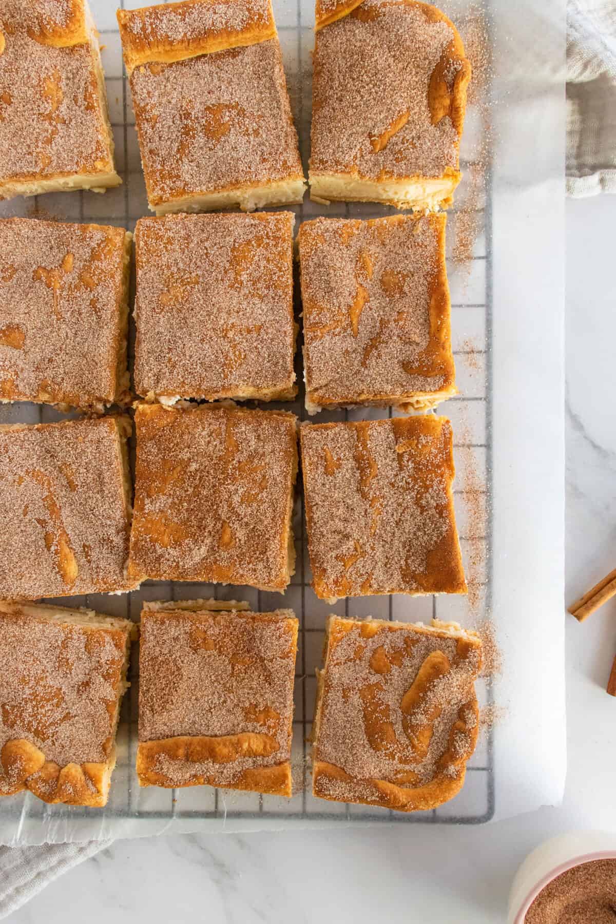 churro cheesecake sliced into bars on a wire rack