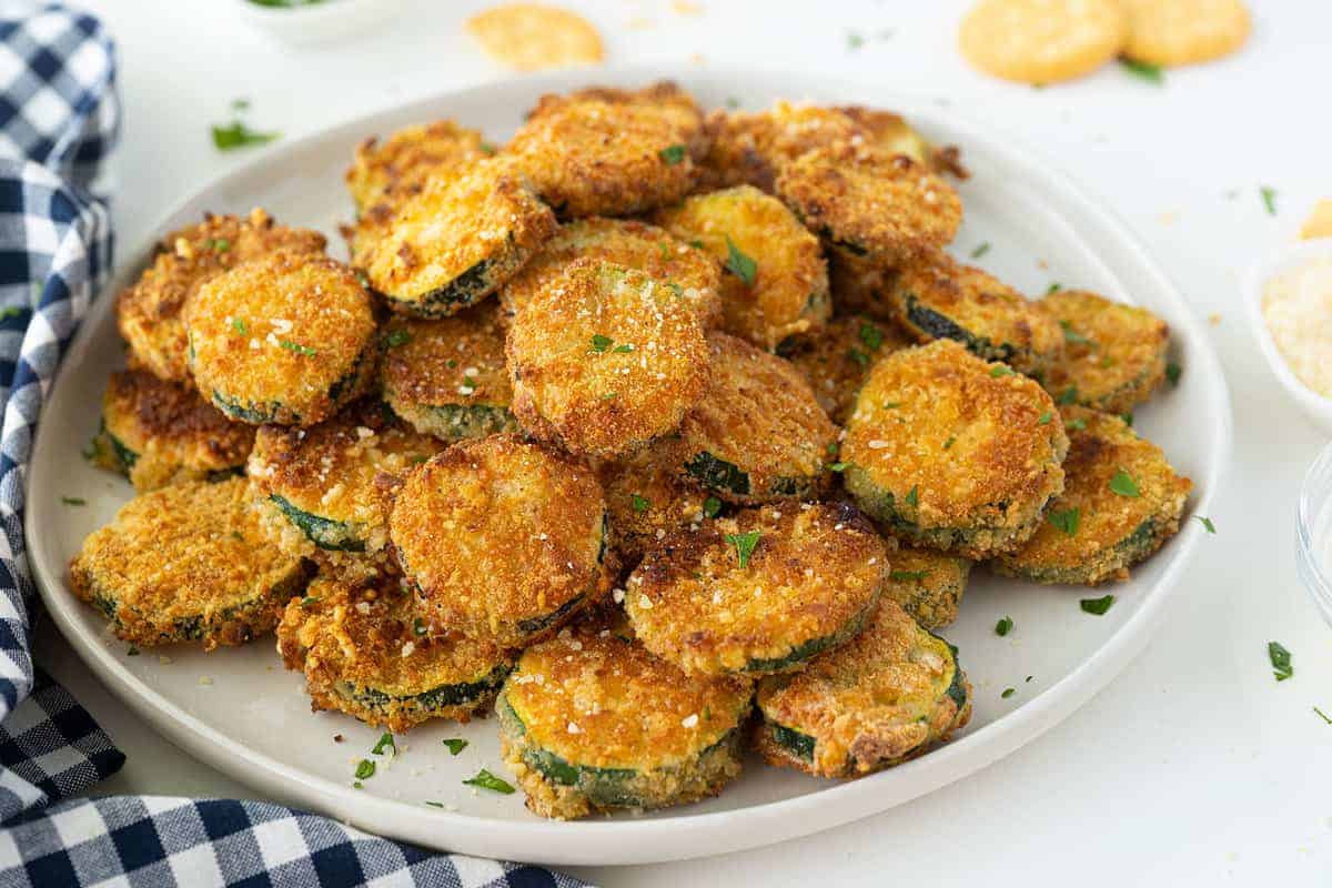Crispy golden-brown fried zucchini rounds on a white plate.
