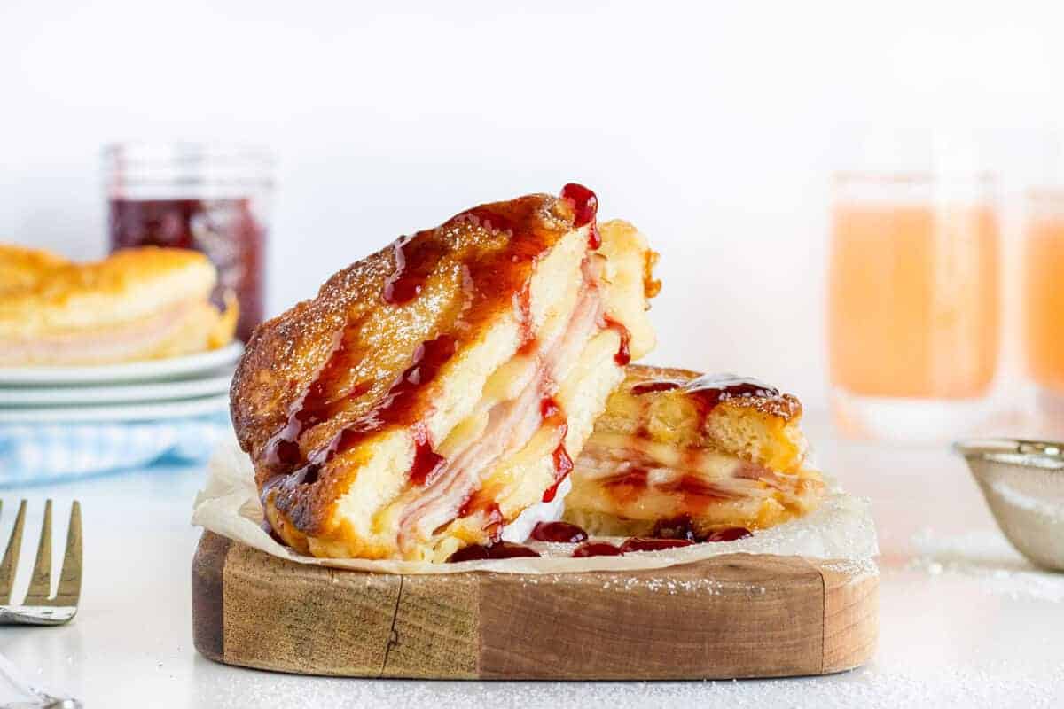 Monte Cristo sandwich stacked on a wooden board with jam on top