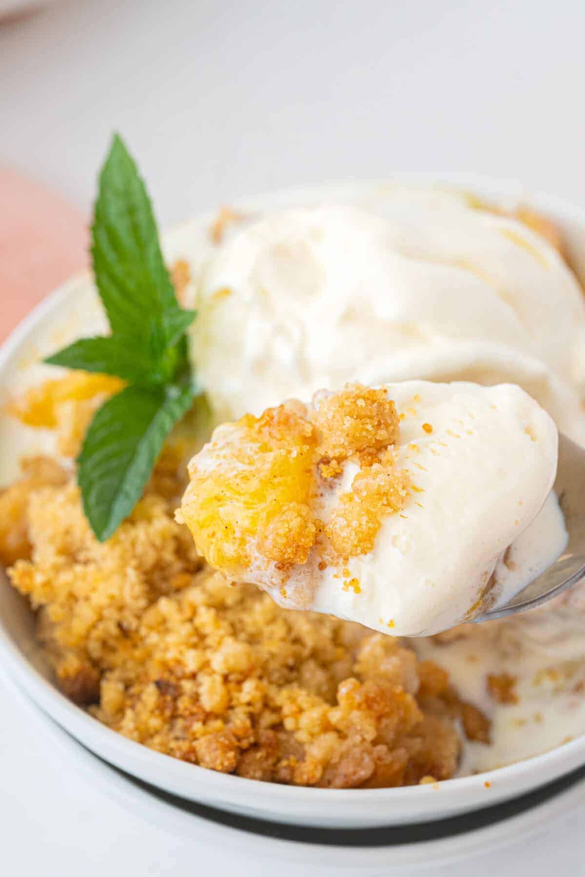 peach crumble on a plate with a scoop of vanilla ice cream on top 