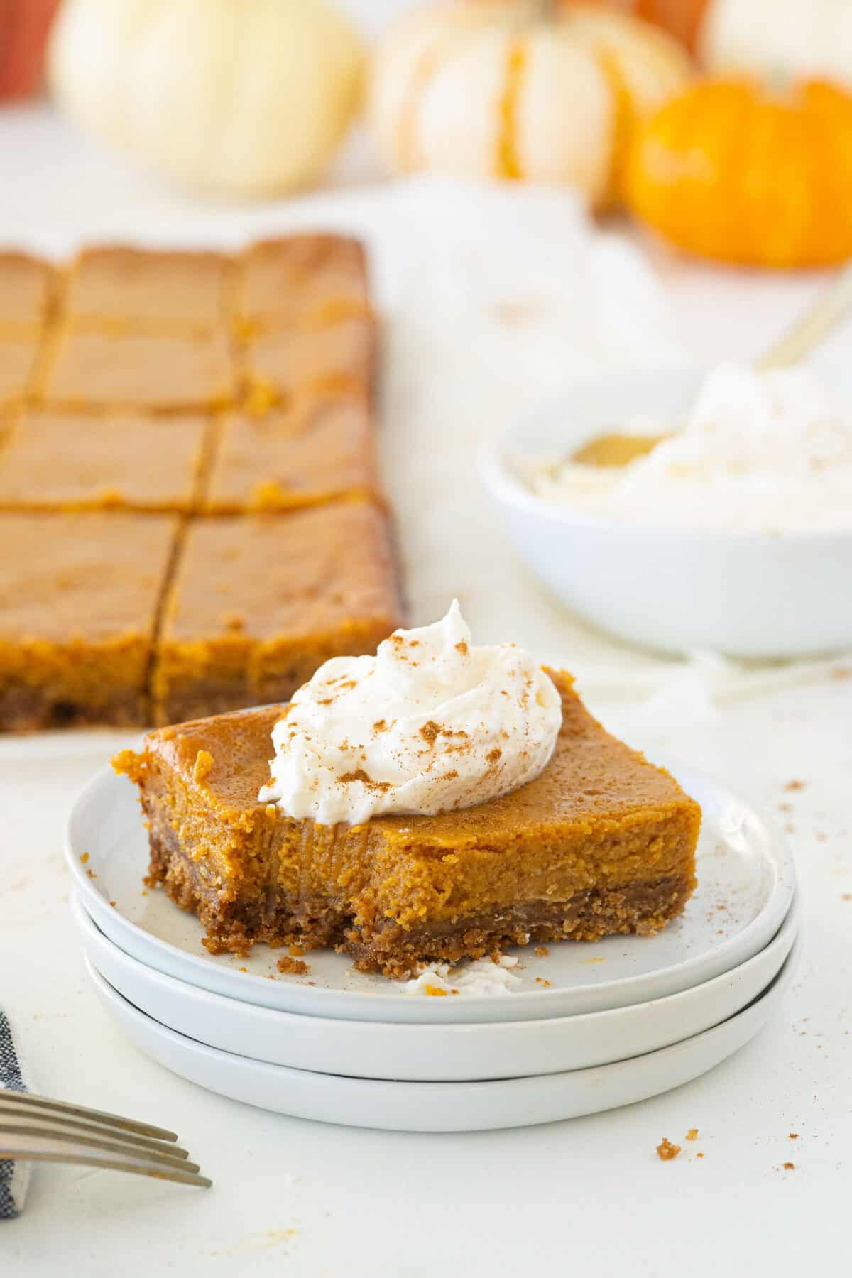 pumpkin pie bars on a white plate with whipped cream on top