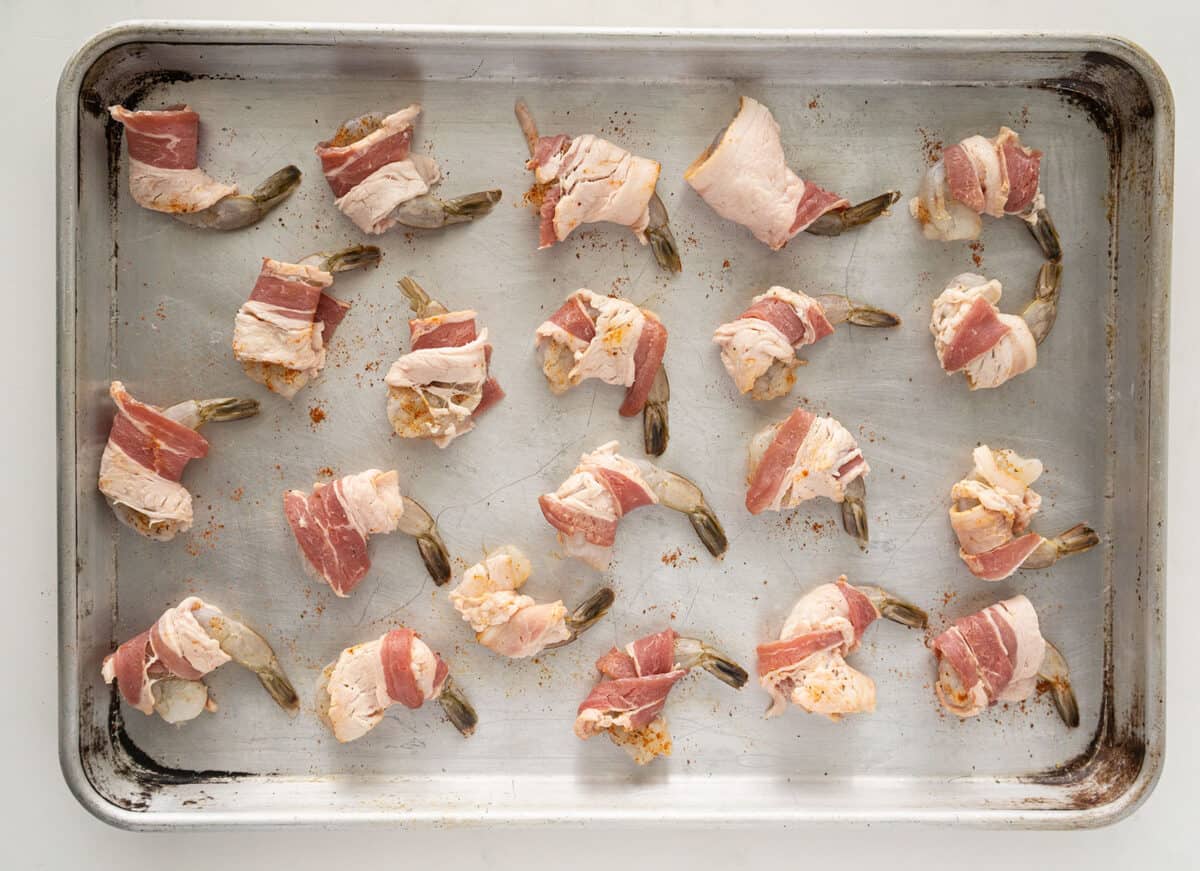 raw bacon wrapped shrimp on a baking sheet