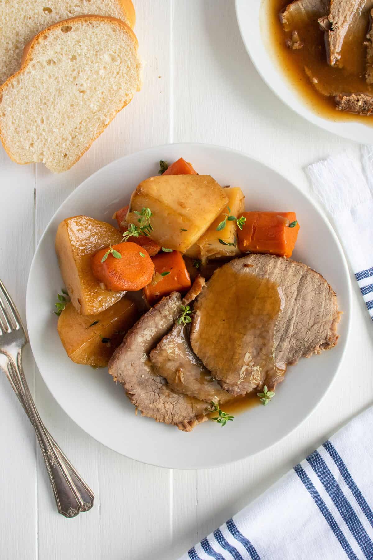 rump roast and vegetables on a white plate with gravy on top