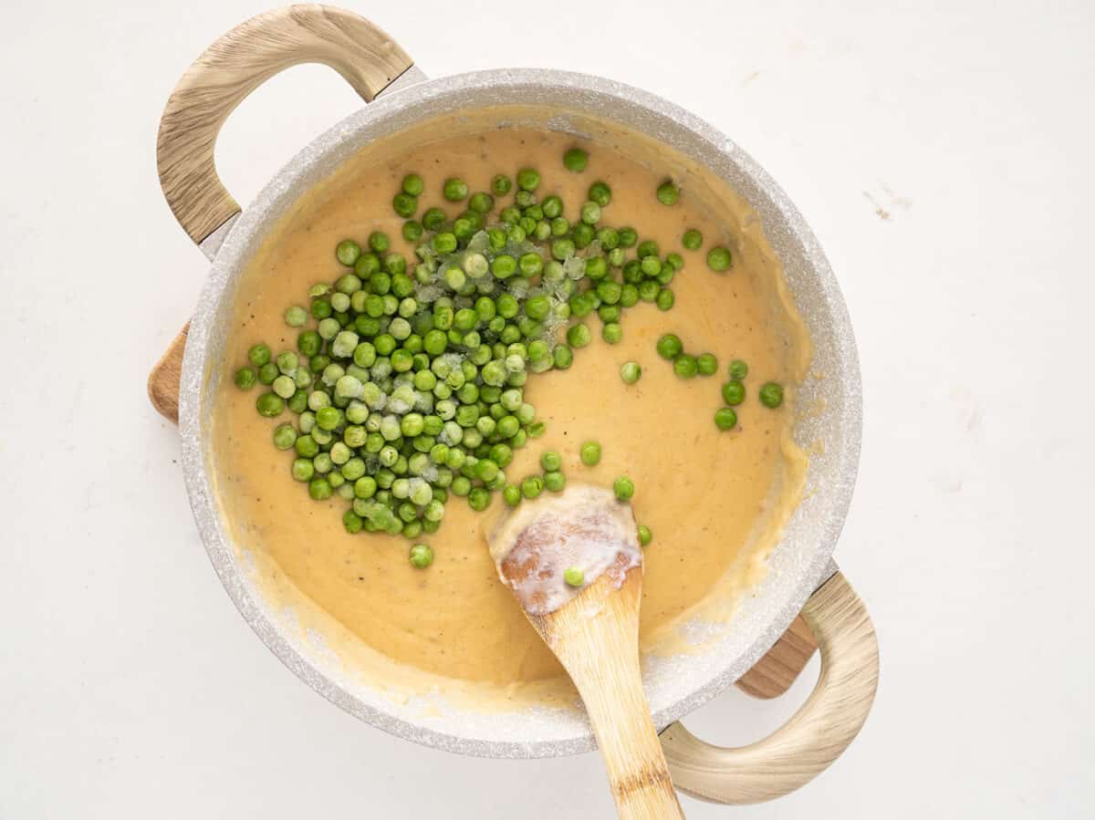 cheese sauce and green peas in a saucepan