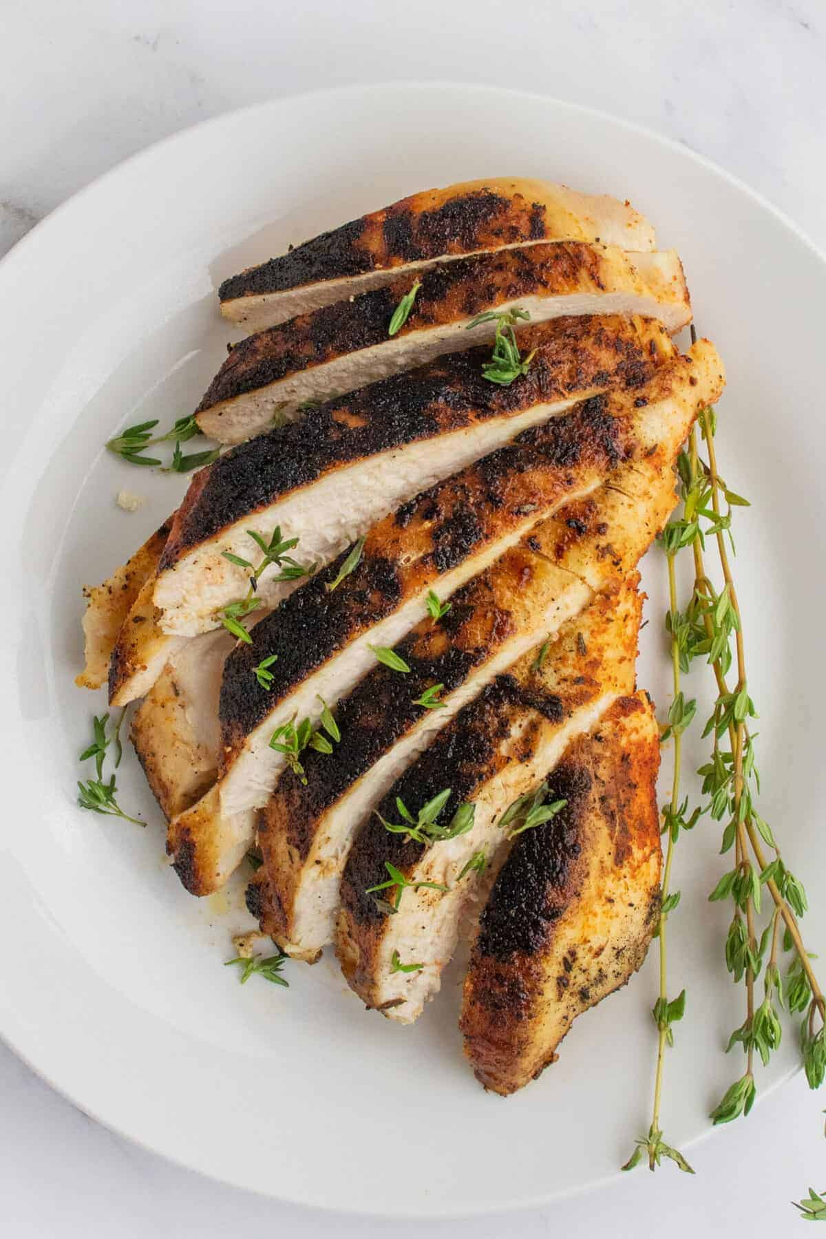 sliced blackened chicken on a white plate 