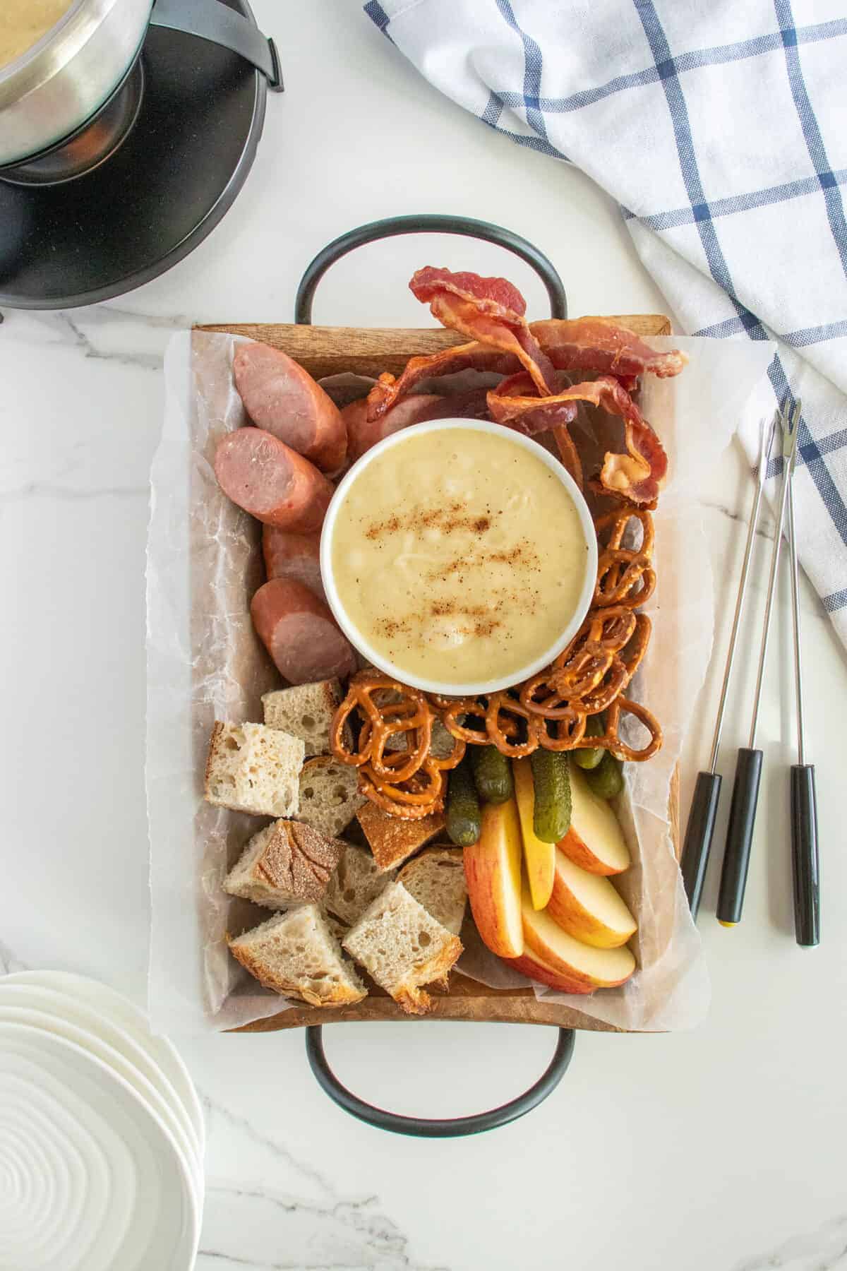 cheese fondue in a white bowl surrounded by food 